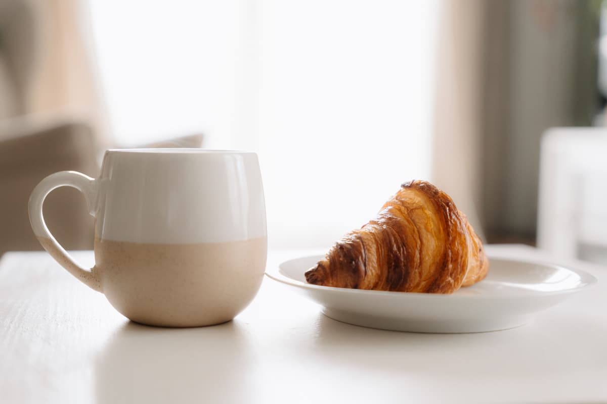 Flaky golden brown croissant on a white ceramic plate
